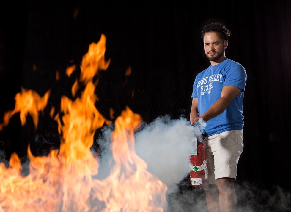 Student with fire extinguisher puts out flame